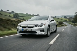 Voiture hybride rechargeable en roulant sur une route de campagne sinueuse
